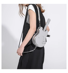 Model wearing a metallic silver guitar-shaped crossbody bag with heart detail and rivets