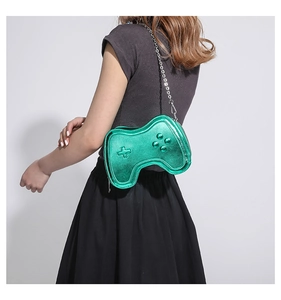 Detail der grünen Umhängetasche in Spiele-Controller-Form mit silberner Kette an einem Model