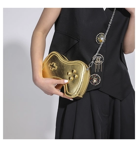 Makroaufnahme der goldfarbenen Mini-Tasche im Controller-Design mit Kette und Anhängern