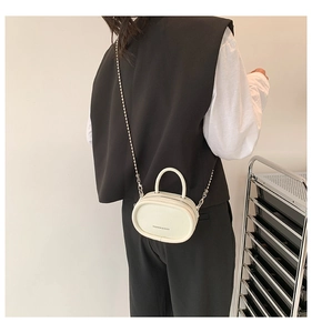 Close-up of a white mini leather crossbody bag with chain strap and top handle