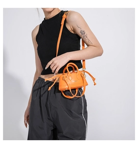 Close-up of vibrant orange mini bag with gold hardware and knotted drawstring details
