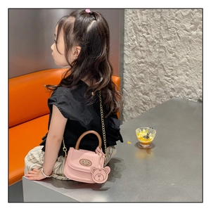 Close-up of pink PU leather girls' mini bag with brown handle and bear charm detail