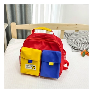 Detail of color-block kids backpack with yellow and blue pockets on white bedding