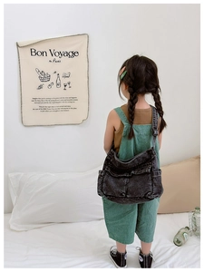 Detailed view of child wearing charcoal denim crossbody bag with functional pockets
