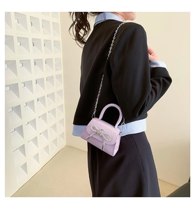 Macro shot of purple mini handbag with silver rhinestone bow and metal chain strap