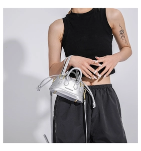Detailed view of a silver mini shell bag with drawstring liner and fashion branding