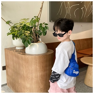 Détail d'un sac de poitrine en toile bleue avec lettres blanches porté par un enfant
