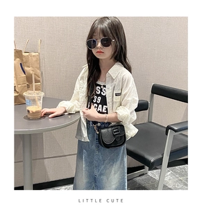 Girl in white collar shirt, black vest and blue denim skirt with a stylish crossbody bag