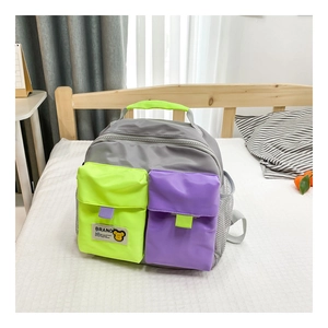 Detail view of a color-block kids canvas backpack with side mesh pockets on a bed