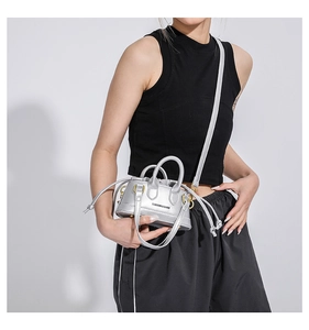 Close-up of a silver mini crossbody bag with drawstring closure and metal handles
