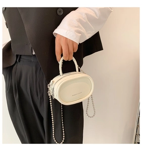 Detailed macro view of white pebble grain faux leather bag with silver bead chain