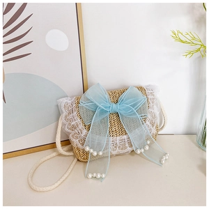 Detail van geweven stro kinderentas met blauwe organza strik en parelaccenten