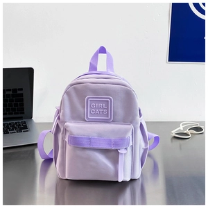 Détail du sac à dos enfant lavande montrant l'étiquette logo et la surface en nylon lisse
