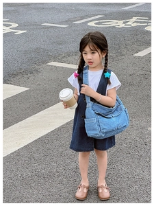 Detail of children's denim crossbody bag featuring functional pockets and adjustable strap