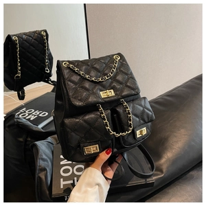 Detail of black quilted leather backpack featuring gold twist locks and chain straps