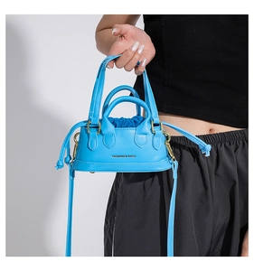 Close-up of bright blue mini handbag featuring drawstring closure and gold hardware