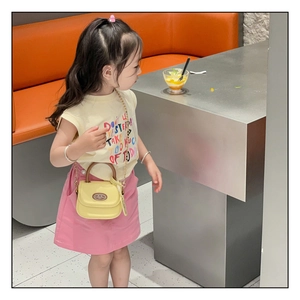 Detail of yellow mini handbag for girls featuring wood-texture handle and gold chain strap