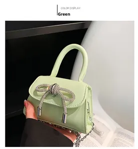 Close-up of a mint green mini handbag with a sparkling rhinestone bow and silver chain link