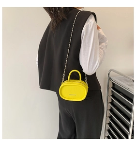 Model view of yellow oval mini crossbody bag with silver chain and litchi texture