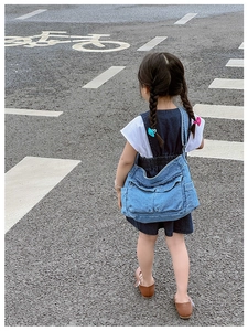 Rear view of a child wearing a blue washed denim crossbody bag with multiple pockets