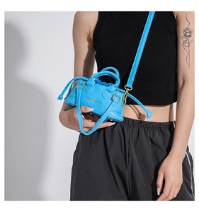 Detail of blue mini crossbody bag featuring side drawstrings and adjustable shoulder strap