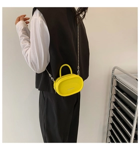 Detail showing bright yellow mini oval bag with litchi texture and silver chain strap