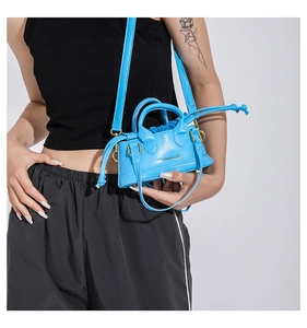 Detail of bright blue mini crossbody bag with gold hardware and fashion lettering