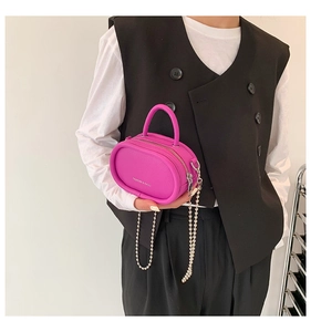 Detail of a mini fuchsia chain bag featuring pebbled texture and metal top handle