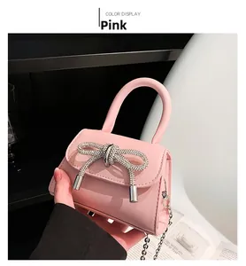 Detailed shot of mini pink hand bag with large rhinestone bow and metallic chain strap