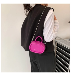 Detail of fuchsia mini oval handbag with silver chain strap and pebbled leather texture