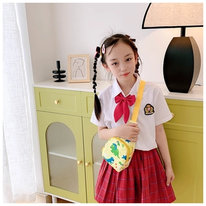 Girl wearing a bright yellow dinosaur printed chest bag with adjustable strap over school uniform