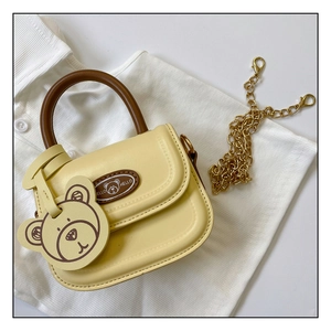 Detail of yellow PU leather kids handbag with brown handle, bear tag, and gold chain