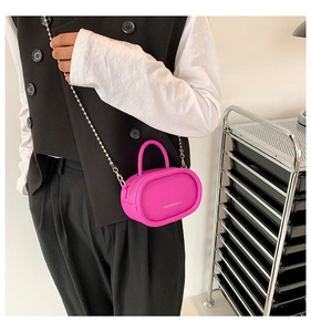 Close-up of mini bright pink oval crossbody bag with silver chain strap and top handle