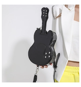 Detailed macro view of the shiny black guitar-shaped crossbody bag with silver metal rivets