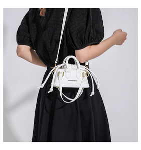 Rear view of a model wearing a white mini crossbody bag with drawstring and golden hooks