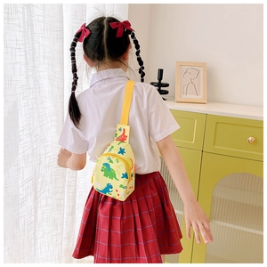 Close-up of yellow dinosaur canvas chest bag worn by child showing cartoon patterns