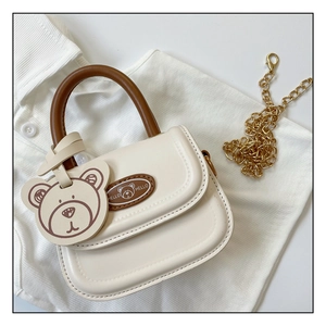 Detail of a beige mini bear handbag with brown handle and golden metal chain strap