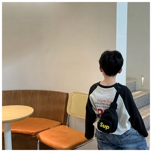 Détail d'un sac de poitrine noir en toile pour enfants avec logo jaune et fermeture éclair