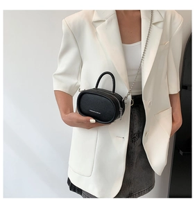 Mini black pebble leather crossbody bag with silver chain strap shown on a model