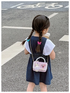 Detail of girls' purple sequin mini crossbody bag with pearl handle worn by a model