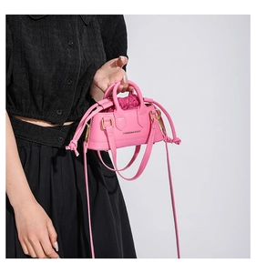 Close-up of bright pink mini handbag with golden text and drawstring lining detail