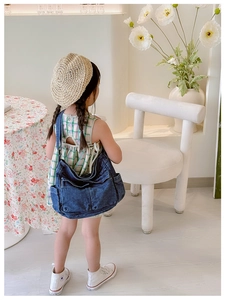 Detail of blue denim crossbody bag for kids with functional front pockets and washed texture