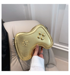 Detailansicht einer goldenen Umhängetasche in Gamepad-Form mit Metallic-Finish und Silberkette