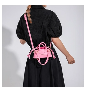 Back view of a vibrant pink mini leather crossbody bag styled on a black puff-sleeve dress