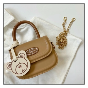 Detail of mini brown leather handbag with teddy bear charm and gold chain strap