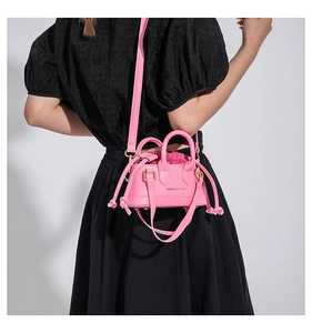 Rear view of a mini pink crossbody bag with gold hardware and a drawstring inner pouch