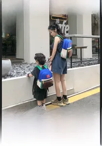 Detail of color-block canvas parent-child backpacks in blue and green with side pockets