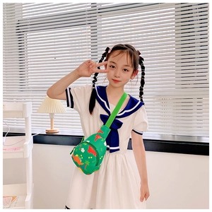 Girl wearing a green cartoon dinosaur chest bag with a fresh navy dress in a room