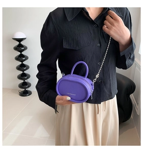 Macro detail of purple egg-shaped mini bag with litchi texture and silver chain strap