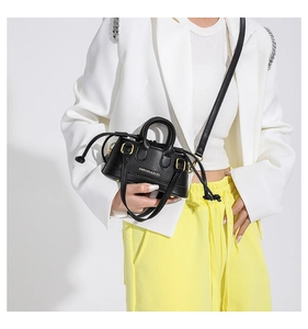 Detail view of mini black handbag featuring Fashion & Bags logo and gold hardware